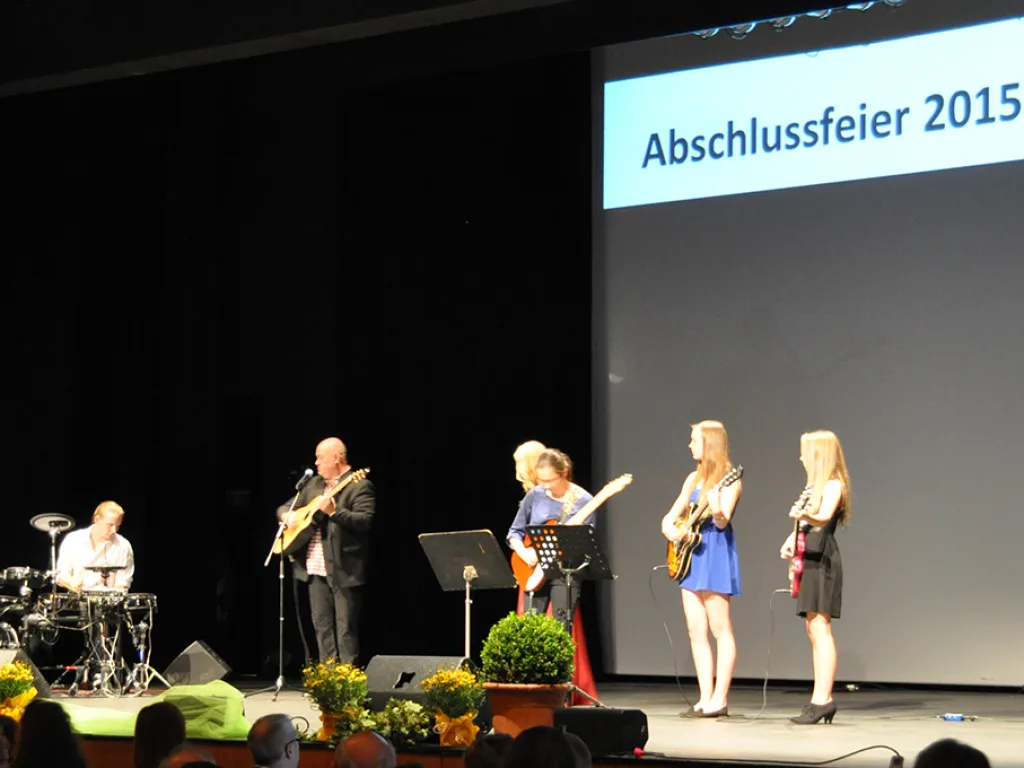 Eine Band spielt vor der Leinwand „Abschlussfeier 2015“.